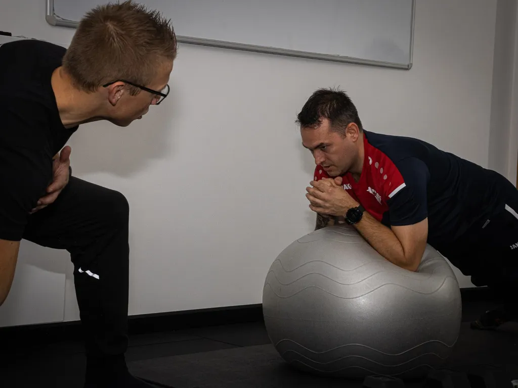 Een Process-coach begeleidt een cliënt tijdens een oefening op een fitnessbal