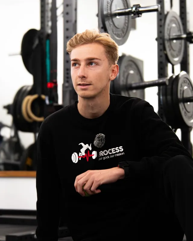 Jorrit Vaes, coach bij Process, zittend voor het rek met halterschijven in de studio